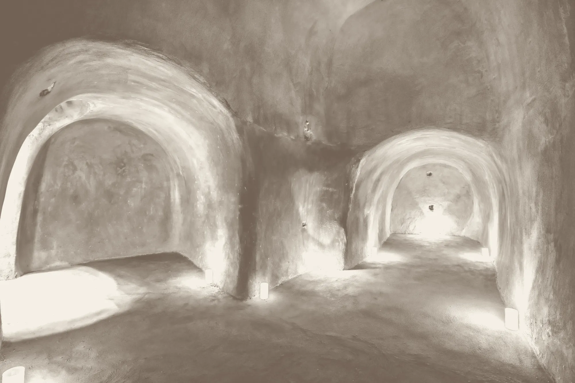 Two arches carved into the volcanic rock of the canava, lit by candles